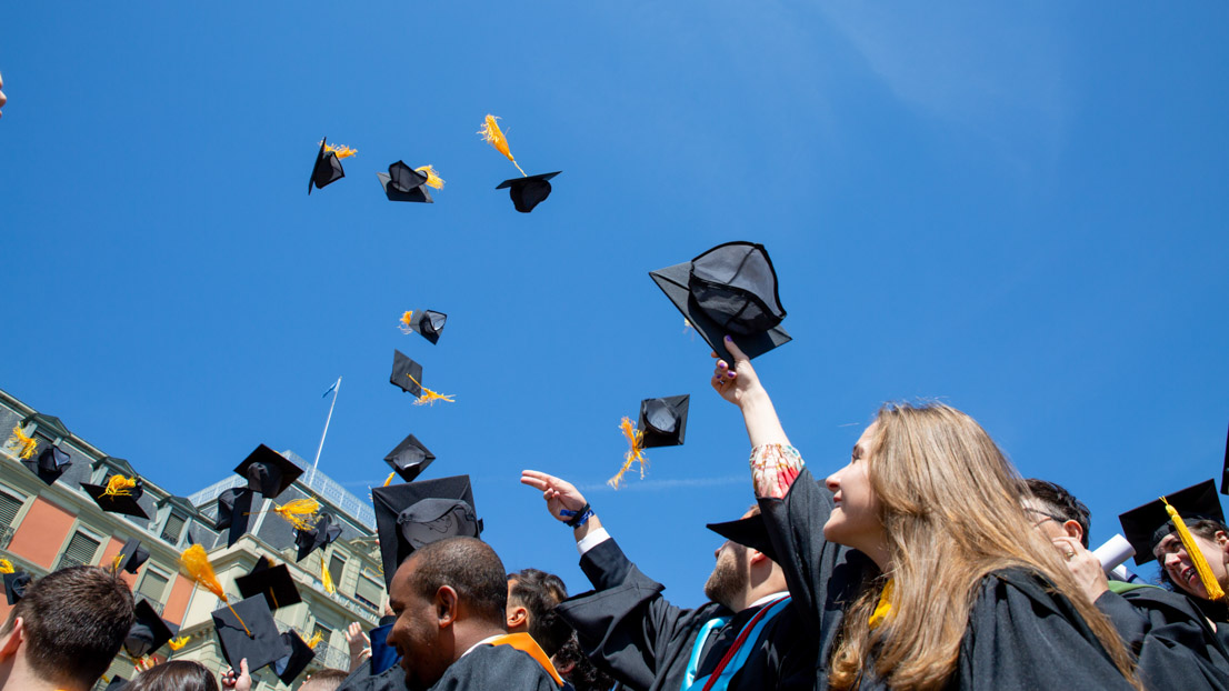 Graduates throwing caps in the air. Webster University in Geneva commencement, 2022. 